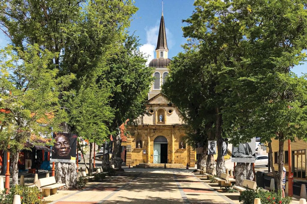 A quaint central square with a large stone church in Sainte-Anne.