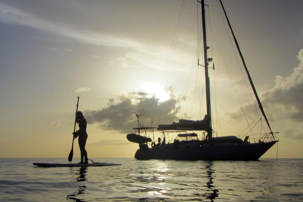 person on a paddleboard near a sailboat