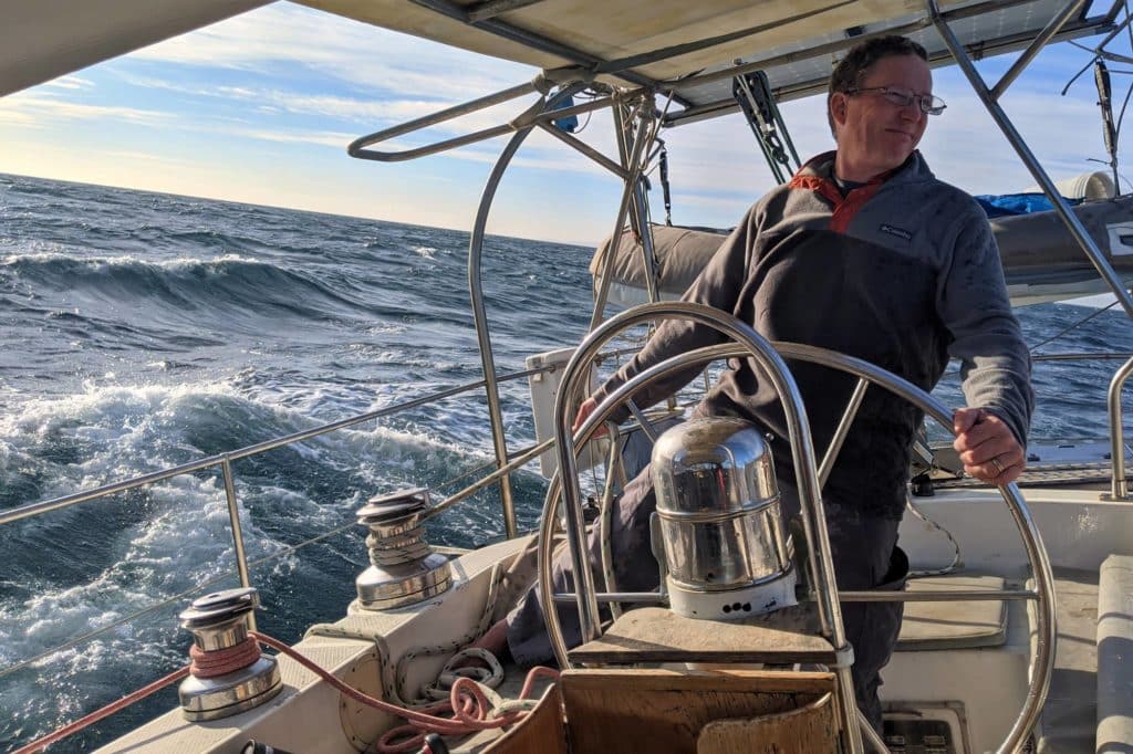 A man at the helm of a sailboat
