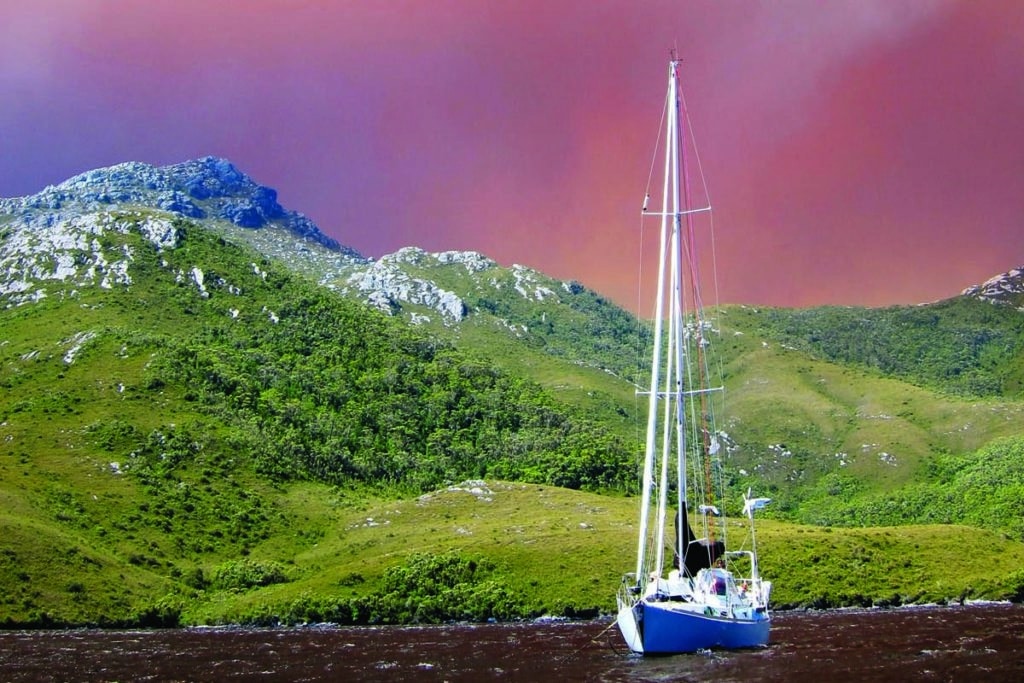 Australian bushfire in the background of a sailboat in Tasmania.