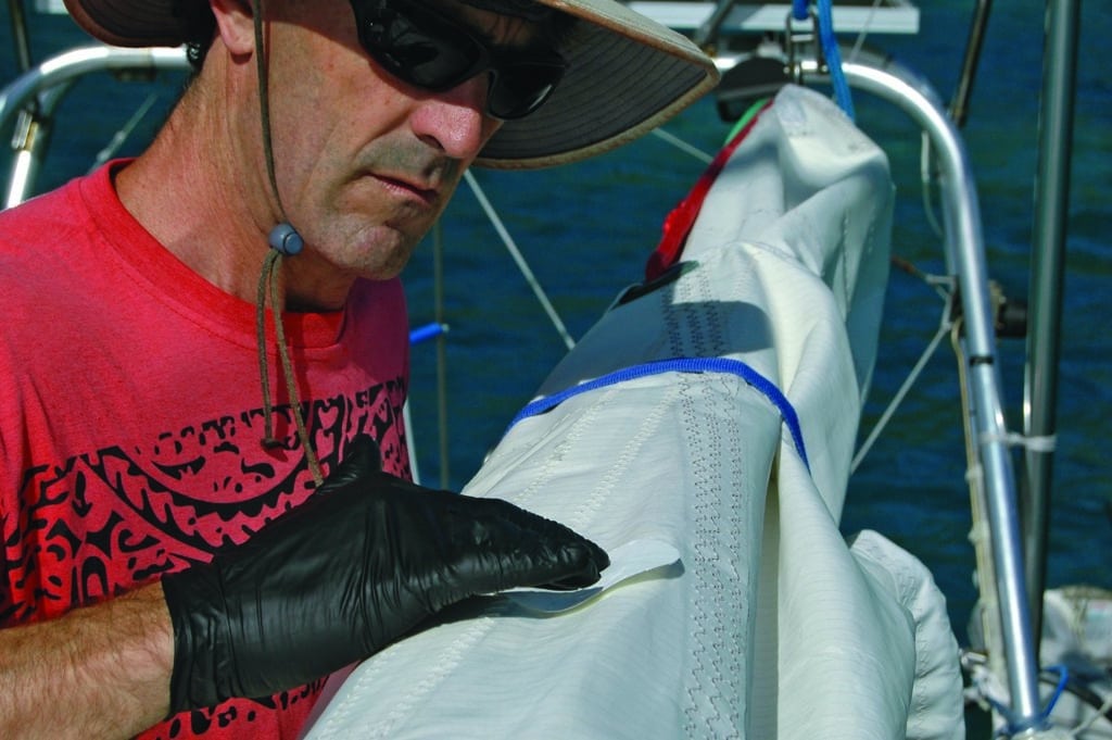 Pressing in adhesive to repair a sail