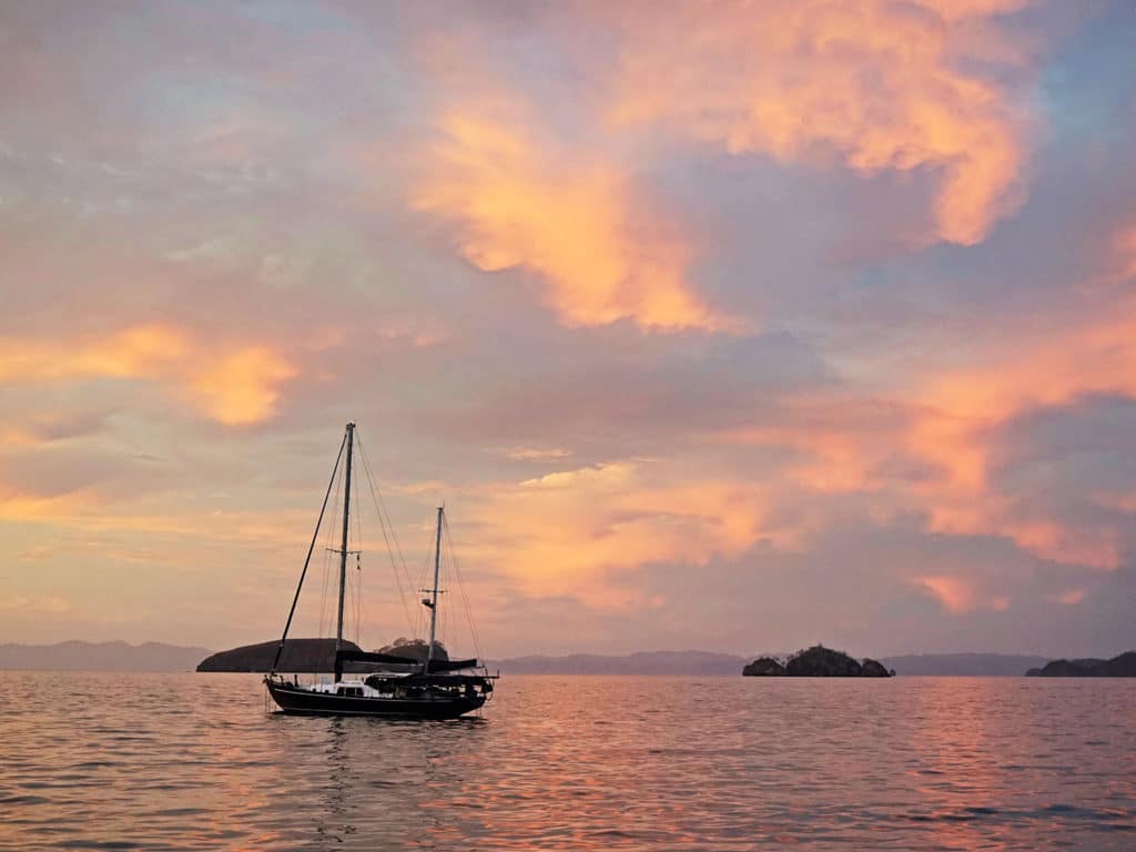 ketch at anchor with pink clouds