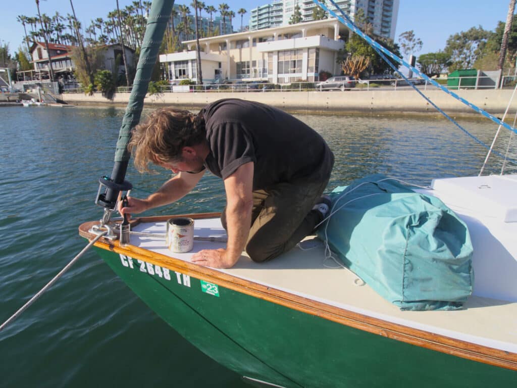 the author adding a third coat of varnish to his sailboat