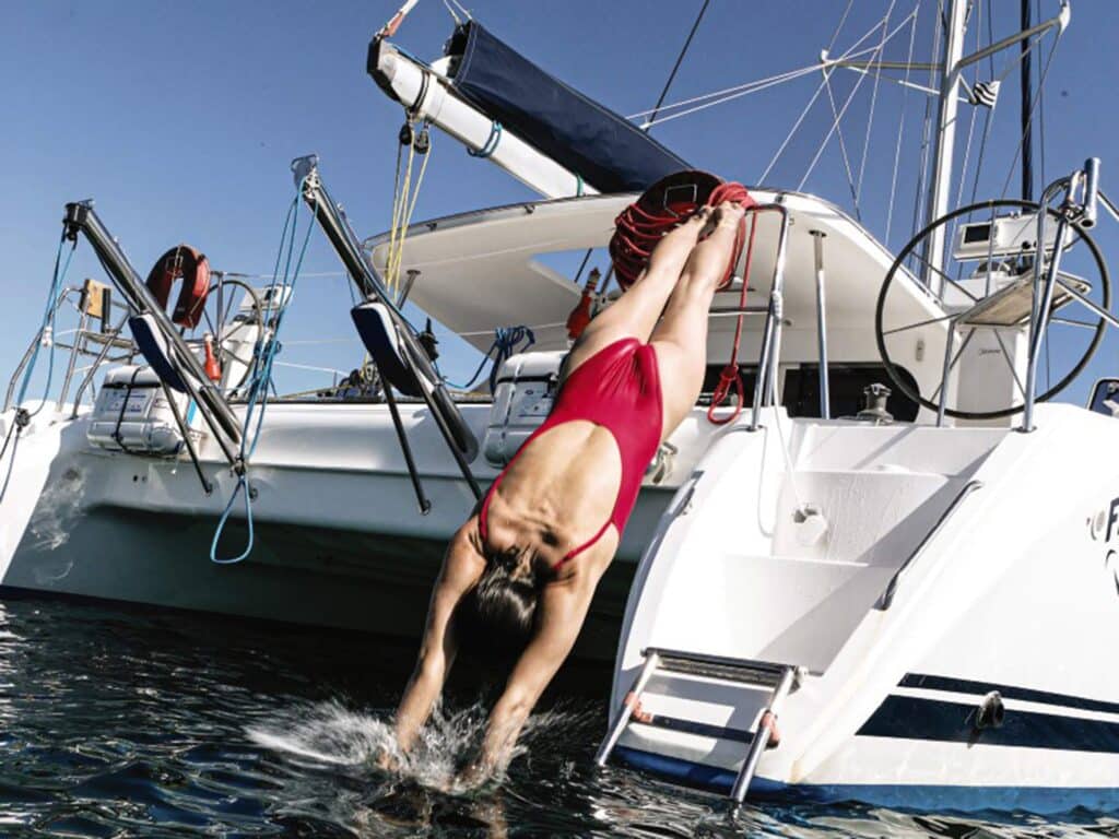 woman diving off of an anchored catamaran
