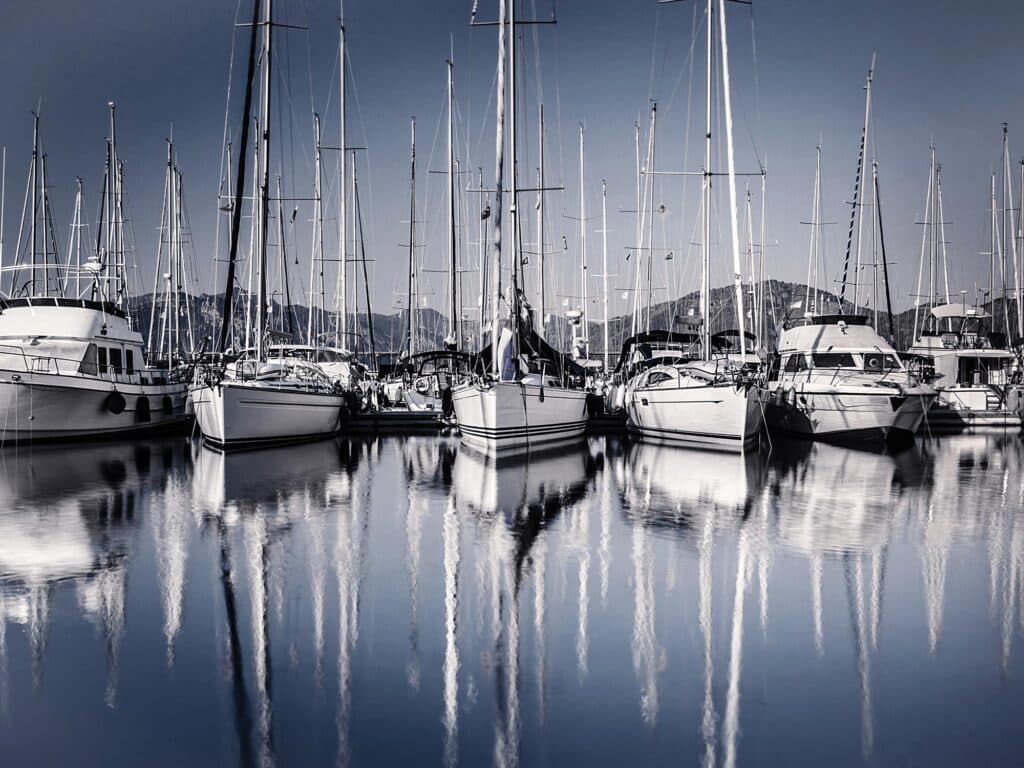 Sailboat harbor in evening, many luxury moored sail yacht in the port, ship mast reflected in water, marina in European city, summer holidays