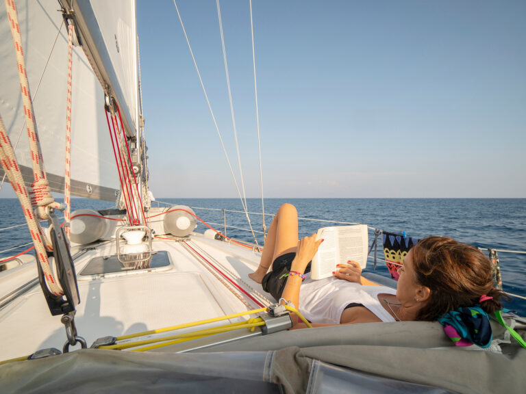 woman relaxing and reading a book on a sailboat