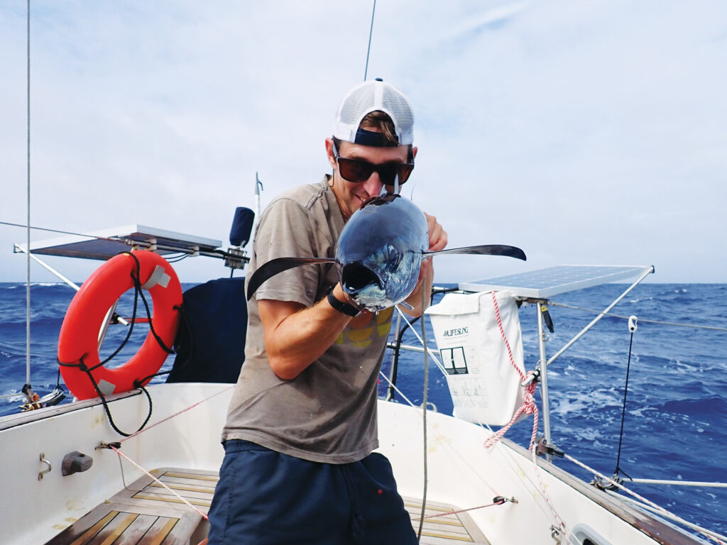 Man holding an albacore tuna on a sailboat