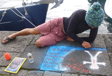 Flyer in Horta Crewmate Xabi Lastapis paints the story of Flyer’s voyage at a rare, empty spot on the Horta waterfront --- the old ferry terminal.