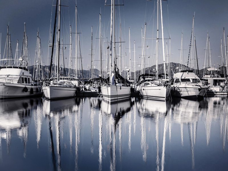 Sailboat harbor in evening, many luxury moored sail yacht in the port, ship mast reflected in water, marina in European city, summer holidays