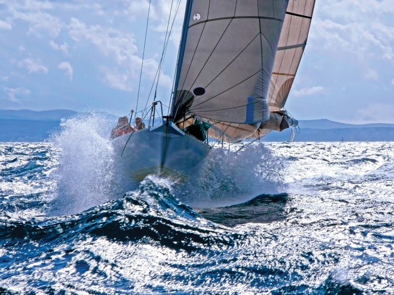 Sailboat breaking through the splashing wave Sailboat breaking with the prow through the splashing wave on the rough sea