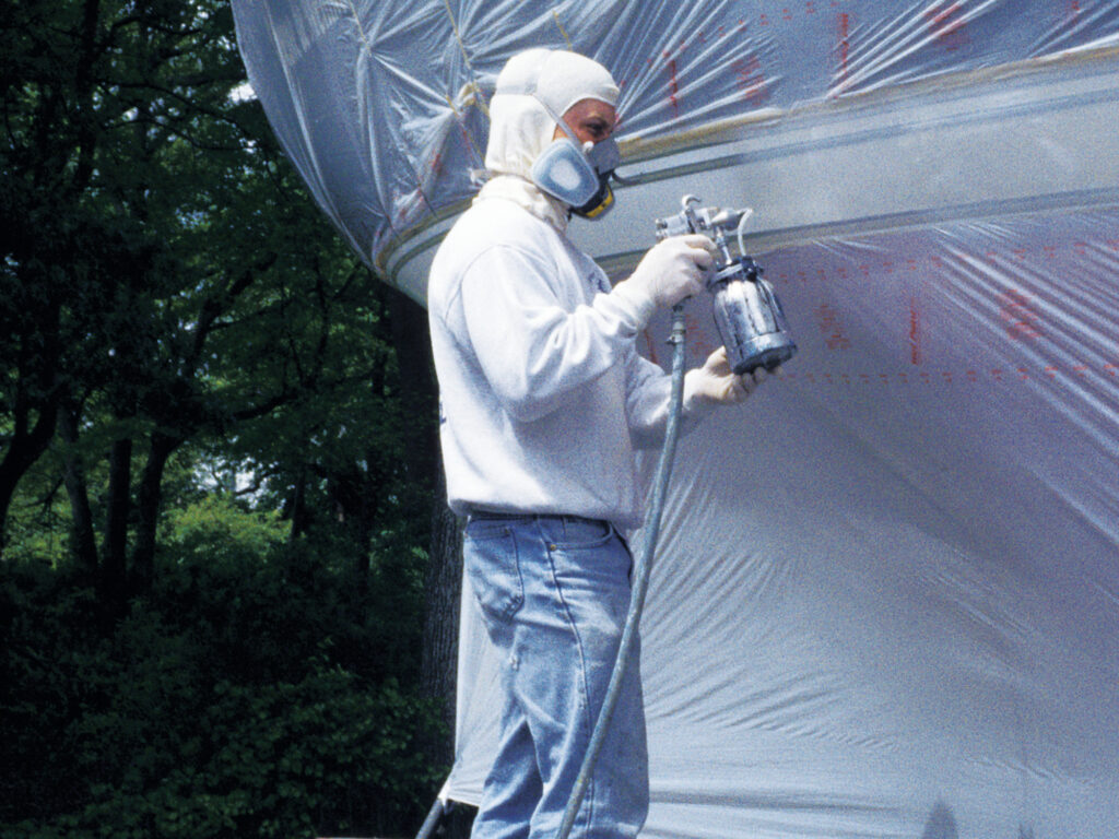 Man adding second coat to sailboat