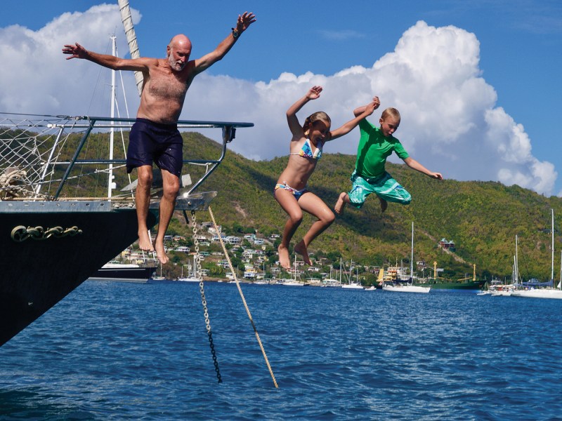 Family jumping off a sailboat into Admiralty Bay