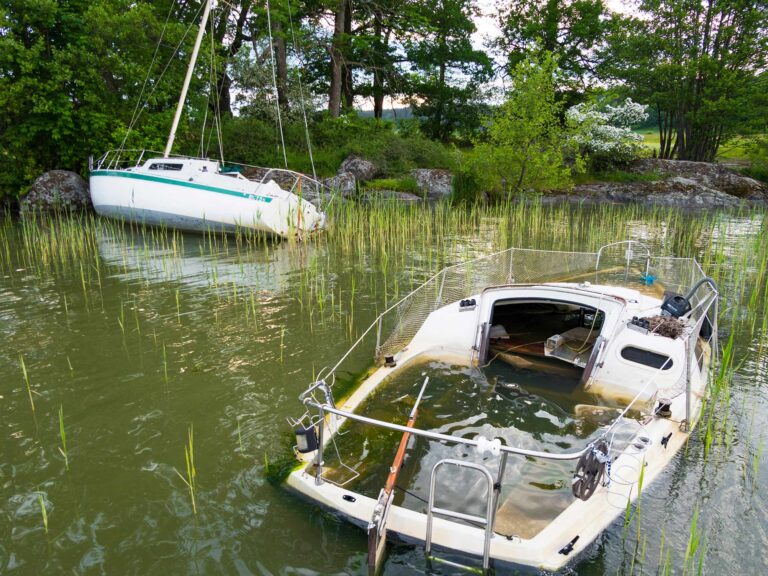 Two abandoned sailboats sit in shallow water in Lake Malaren.
