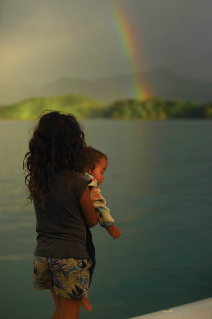 mother holding a baby looking at a rainbow