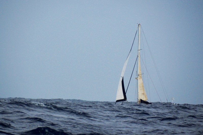 A Sailboat barely visible between waves