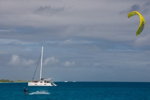 An anchored catamaran with a kite surfer nearby