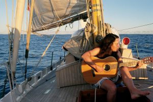 Sailor playing guitar on sailboat deck